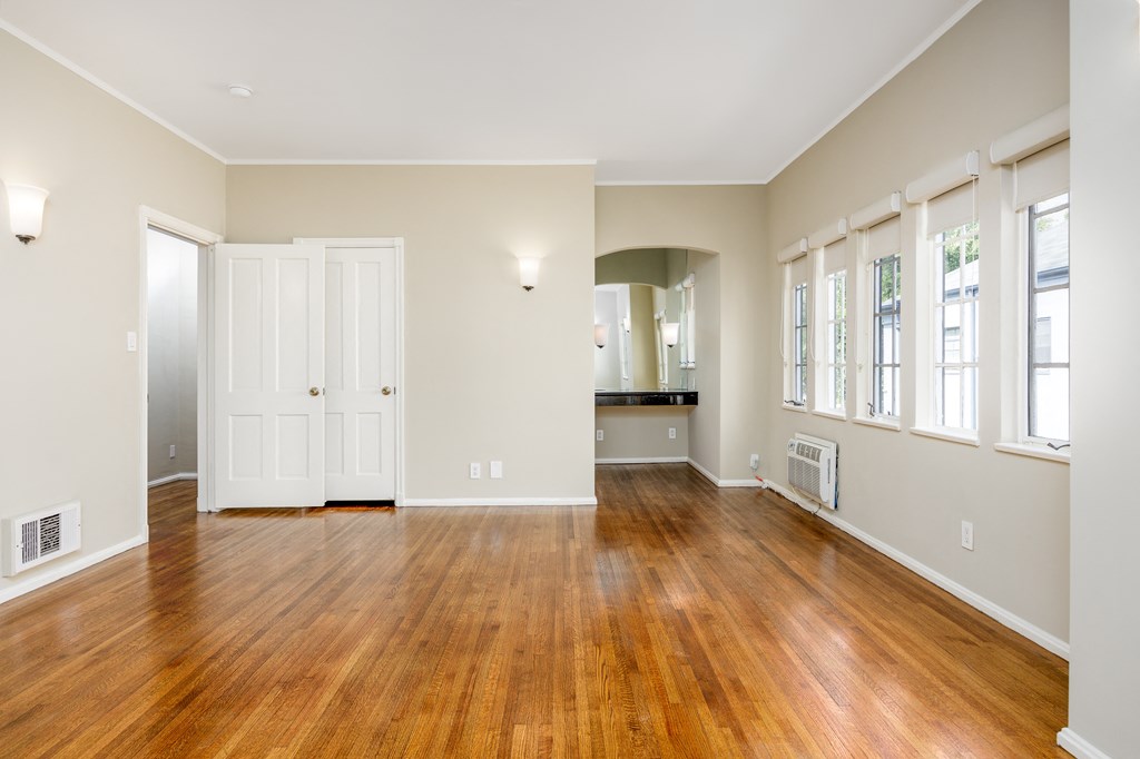an empty living room with wood flooring and windows