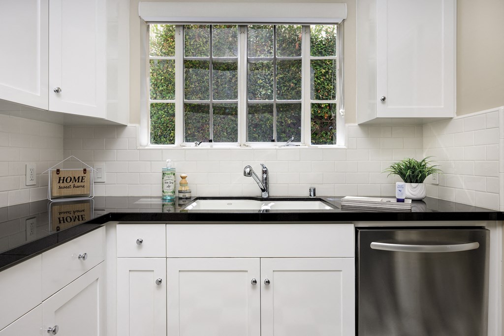 a kitchen with white cabinets and a sink and a window