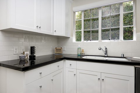 a kitchen with white cabinets and black counter top and a sink