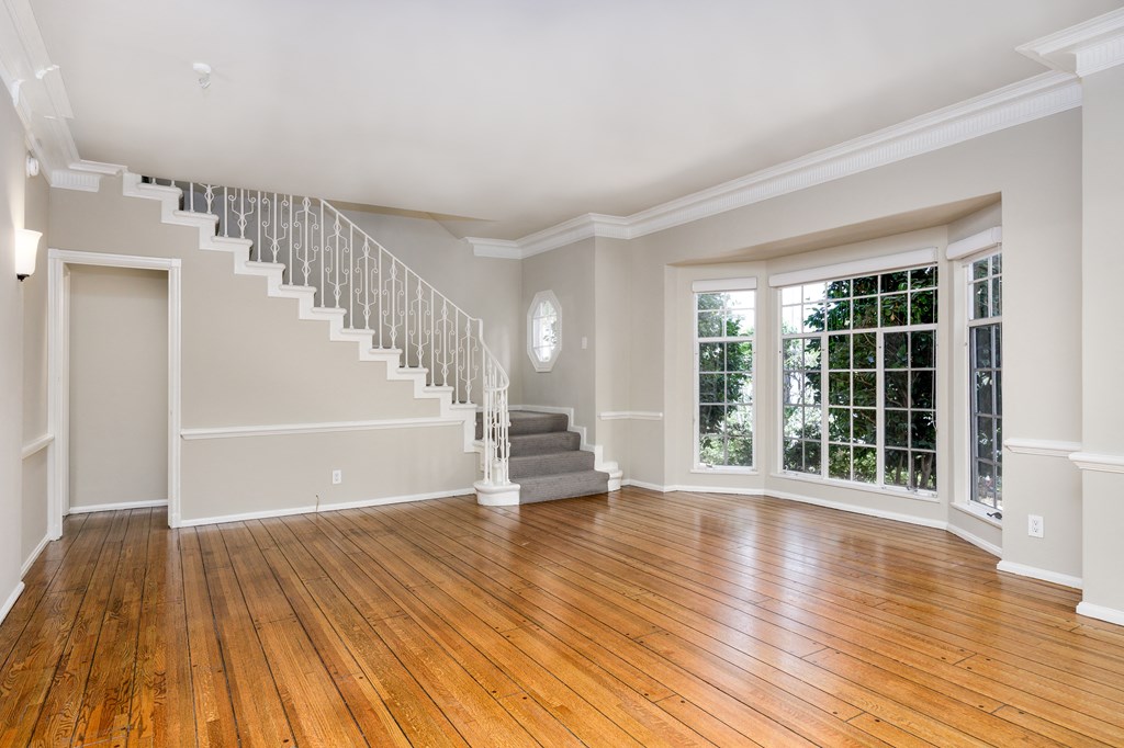 an empty living room with a staircase and wood floors