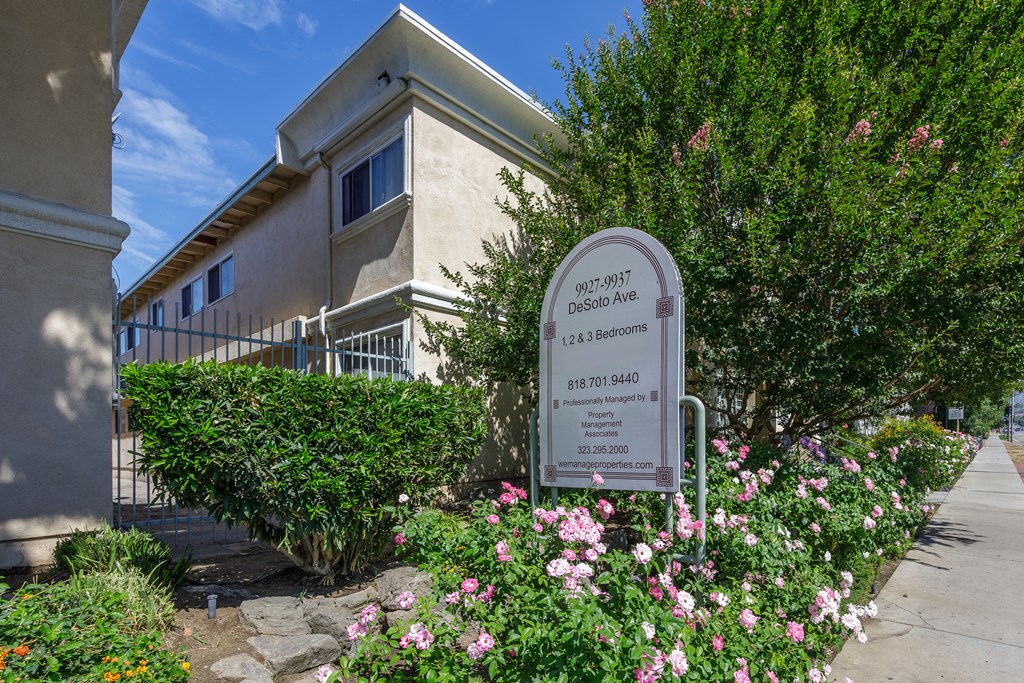 a building with a sign and flowers in front of it