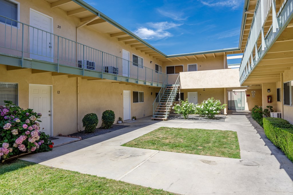 the courtyard of an apartment building with a lawn and a staircase