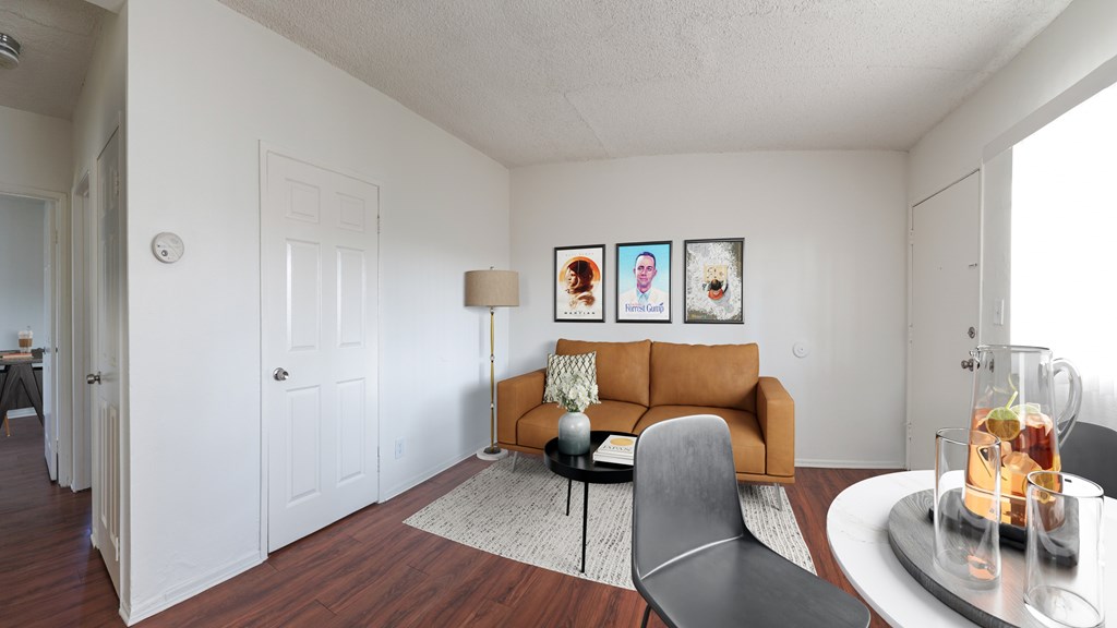 A living room with a brown couch, a grey chair, and a coffee table with a vase of flowers on it.