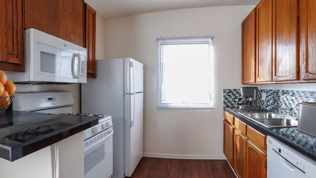 A kitchen with white appliances and wooden cabinets.