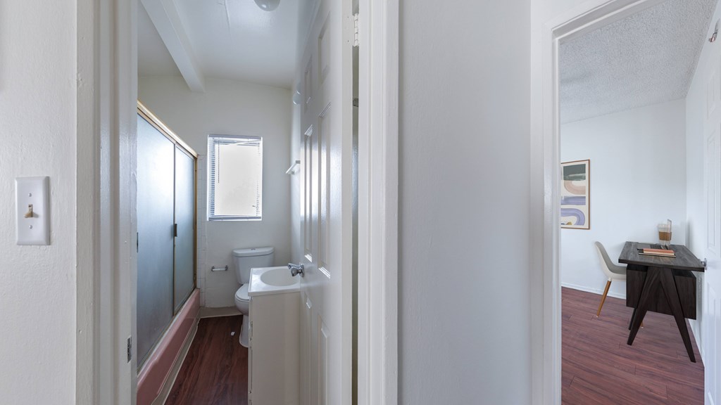 A bathroom with a toilet, sink, and mirror.