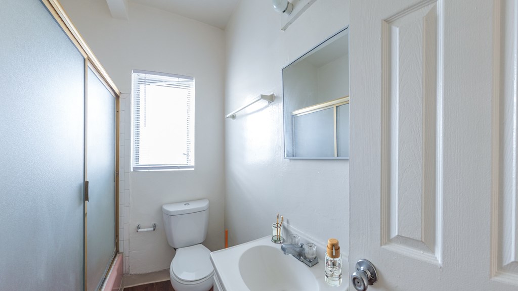 A white bathroom with a toilet, sink, and mirror.