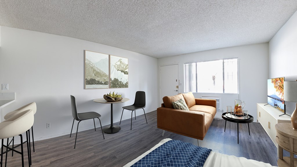 A living room with a brown couch, a dining table with chairs, and a television.