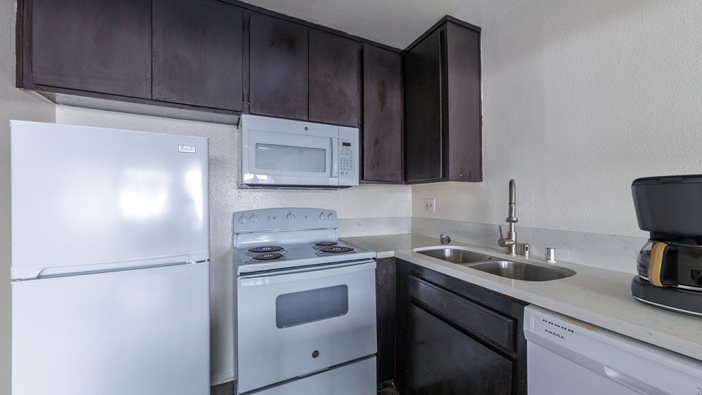 A kitchen with white appliances and brown cabinets.