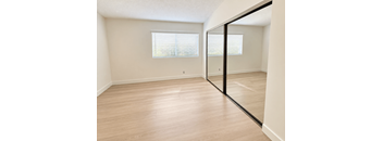 A room with wooden flooring and a large mirror on the wall.
