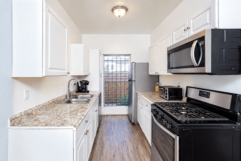 A kitchen with black appliances and white cabinets.