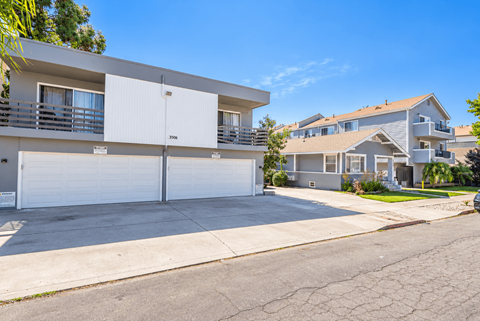 A white two-story apartment building with a garage door in the middle.