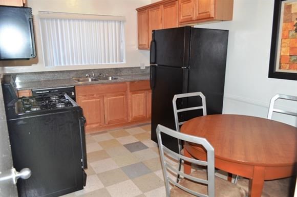 a kitchen with a wooden table and a black refrigerator