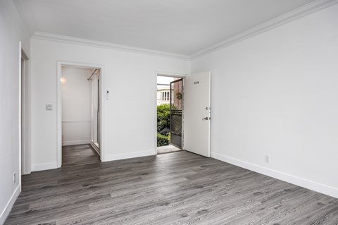 A room with white walls and wooden flooring with two doors.