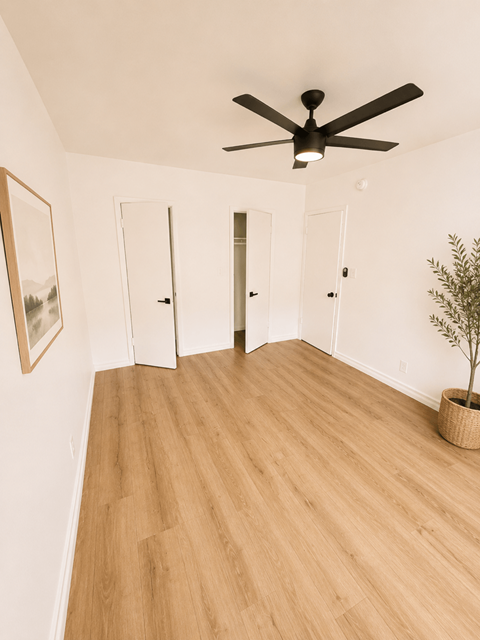 A room with a ceiling fan and a plant in a basket.