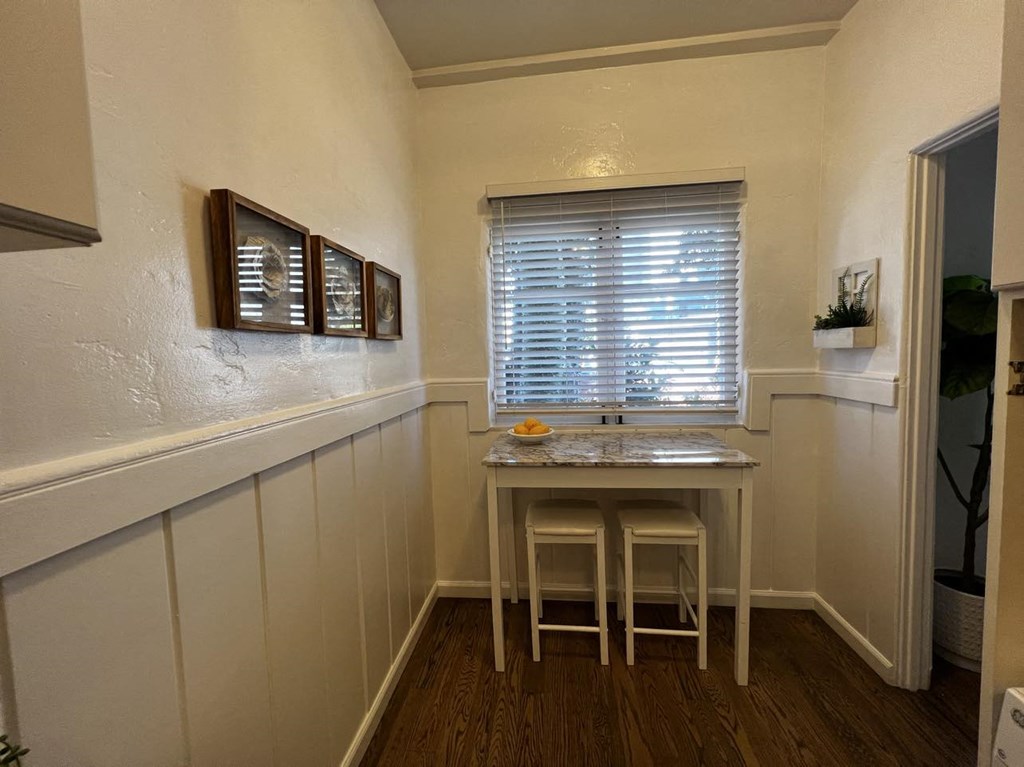 a kitchen with a table and two stools in front of a window