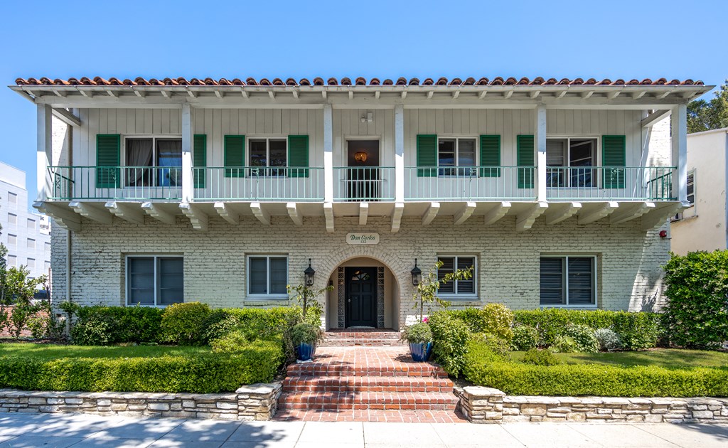 a mansion with a white brick facade and green shutters