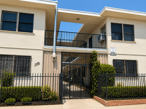 A two-story beige building with black railings and a black gate.