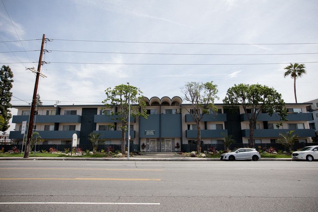 an apartment building on the corner of a street with cars