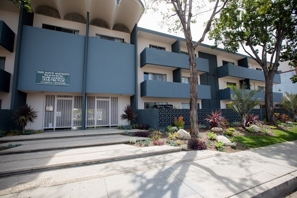 the front of a building with a blue facade and a sidewalk