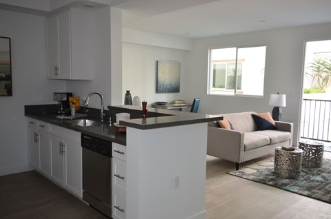 A modern kitchen with white cabinets and a black countertop.