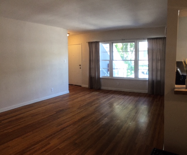 an empty living room with wood floors and a window