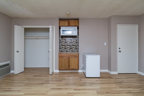 A room with a white fridge and a stone wall.