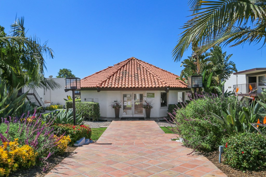 A house with a red tile roof and a brick pathway leading to the front door.