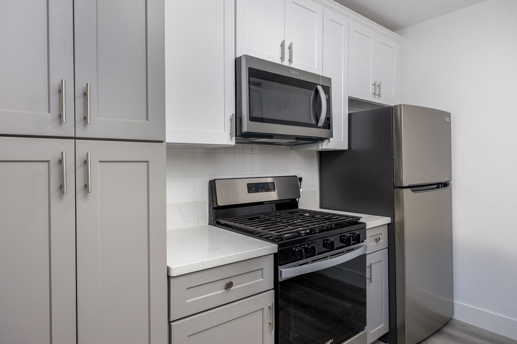 a kitchen with white cabinets and a stove and a microwave