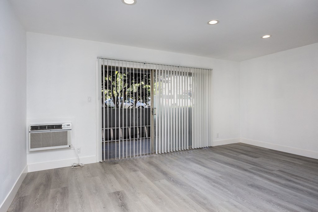 a living room with white walls and a sliding door to a patio
