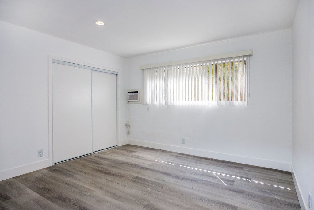 an empty room with white walls and wood flooring and a white door and window