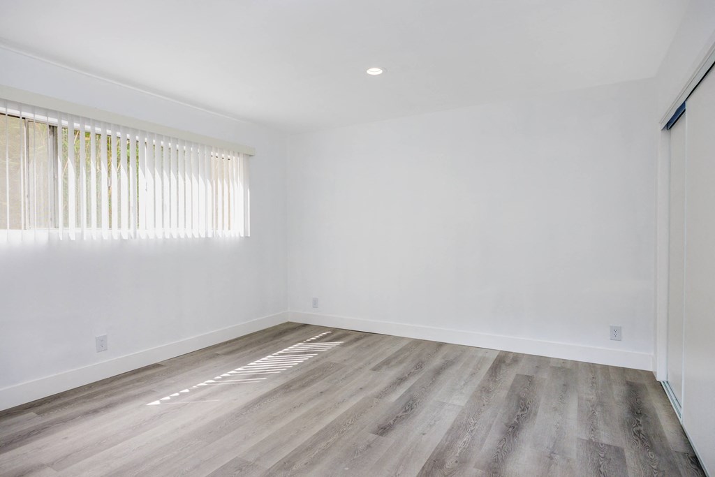an empty room with white walls and wooden floors