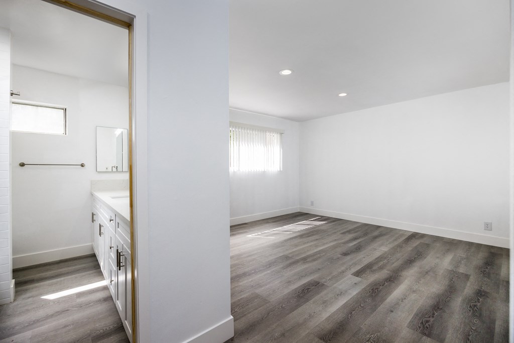 an empty living room and kitchen with white walls and wood flooring