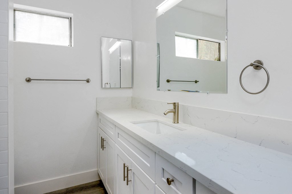 a bathroom with white cabinets and a sink and a mirror