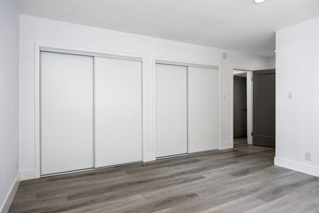 an empty room with white walls and wood floors