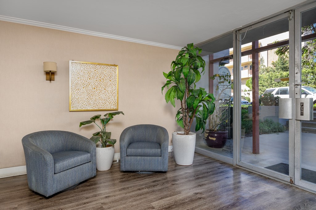 a living room with two chairs and potted plants