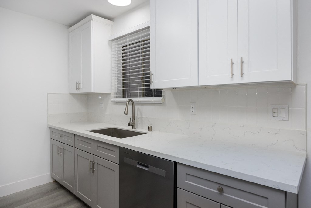 a kitchen with white cabinets and a sink and a window