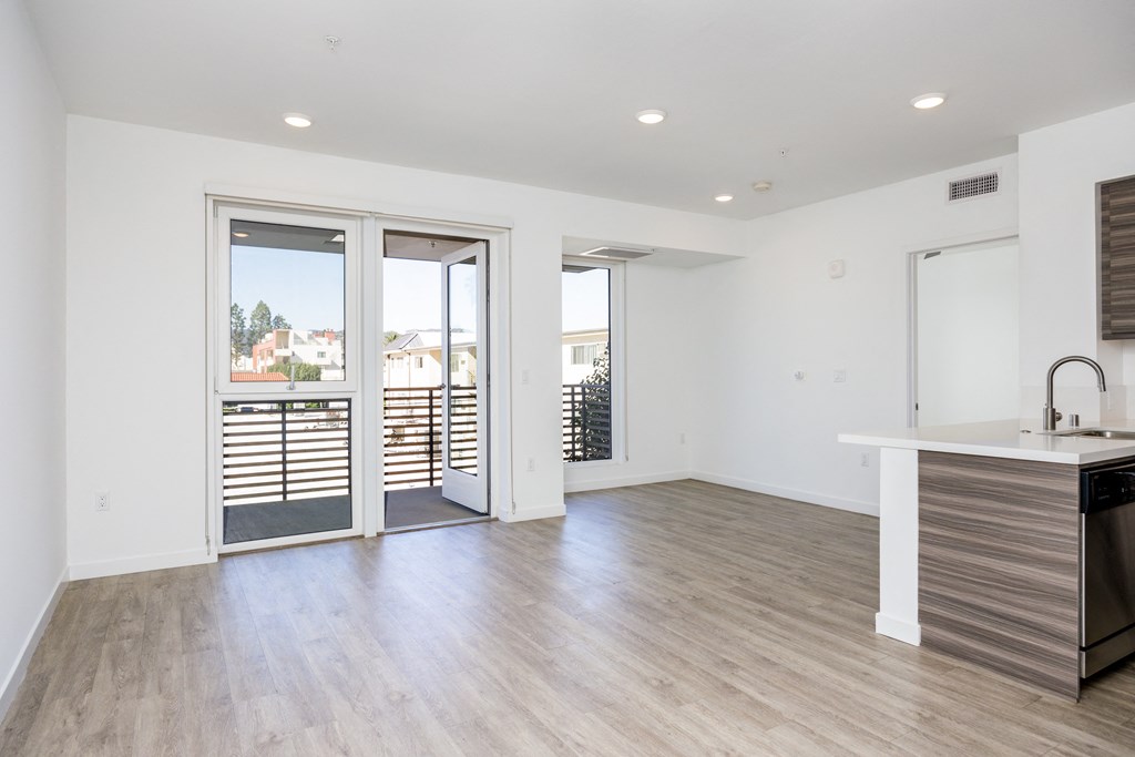 a living room and kitchen with sliding glass doors to a balcony