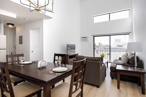 a living room and dining room with a wooden table and chairs and a large window