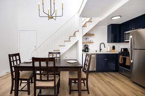 A kitchen with a table and chairs and a staircase.