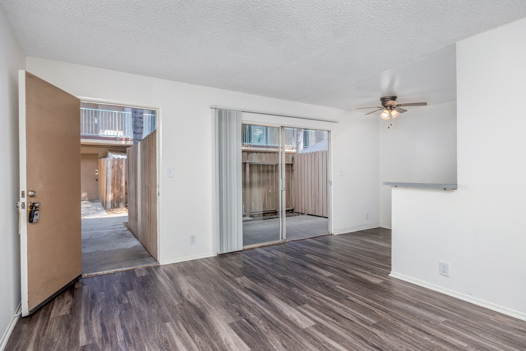 an empty living room with a ceiling fan and sliding glass doors to a patio