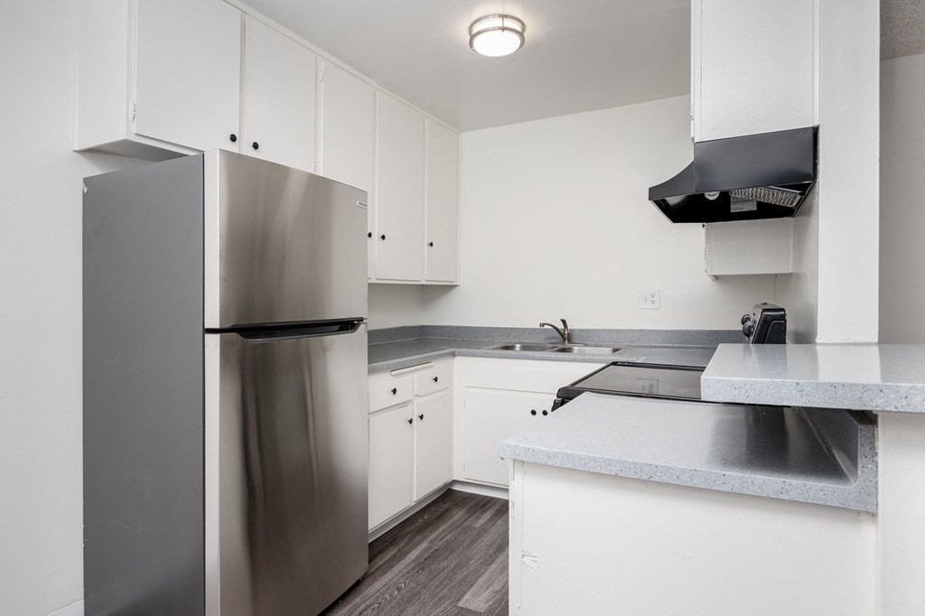 a kitchen with white cabinets and a stainless steel refrigerator