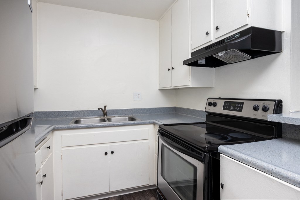 an empty kitchen with white cabinets and black appliances