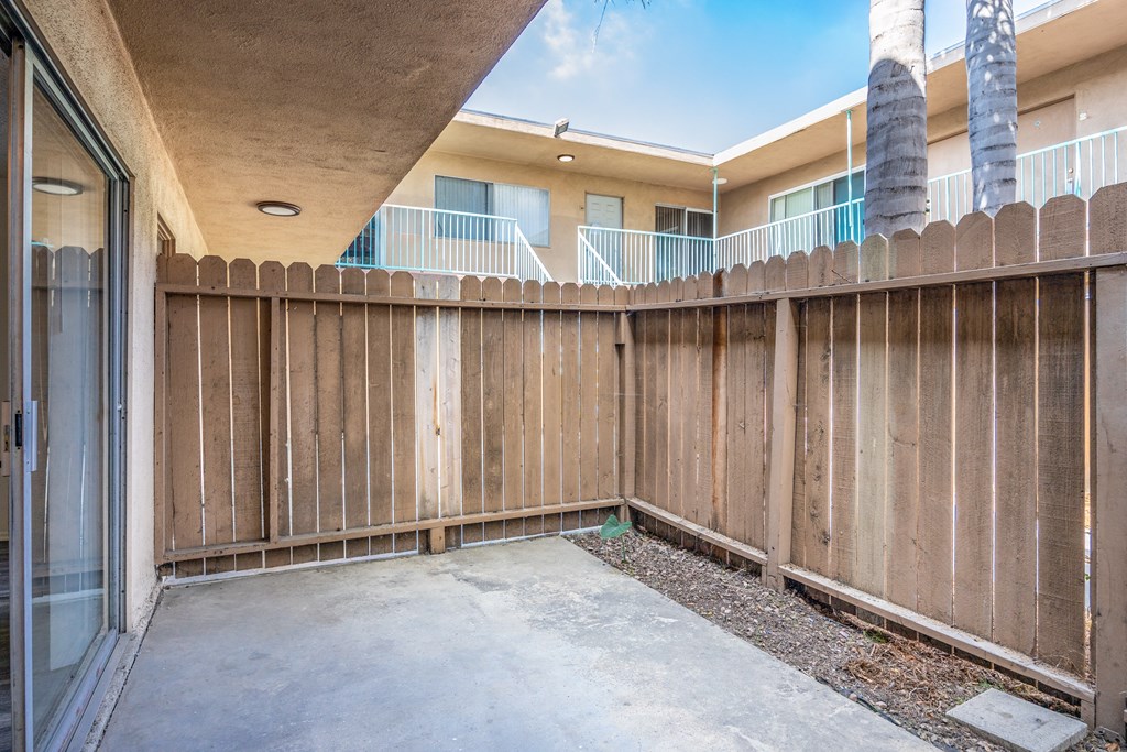 an empty patio with a wooden fence in front of an apartment building