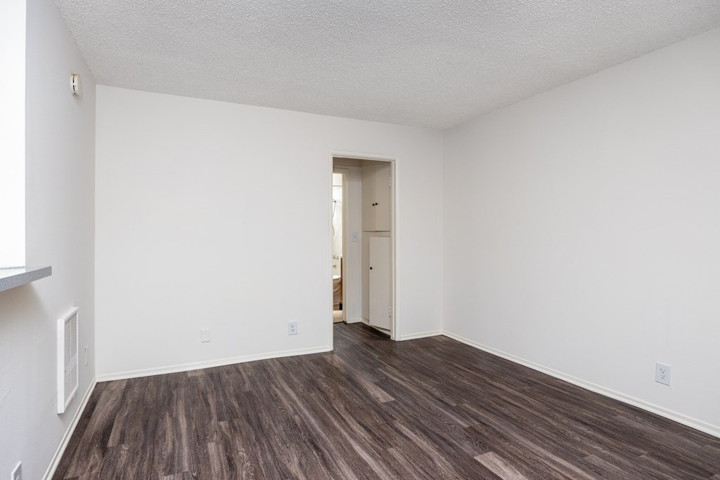 an empty living room with white walls and wood flooring