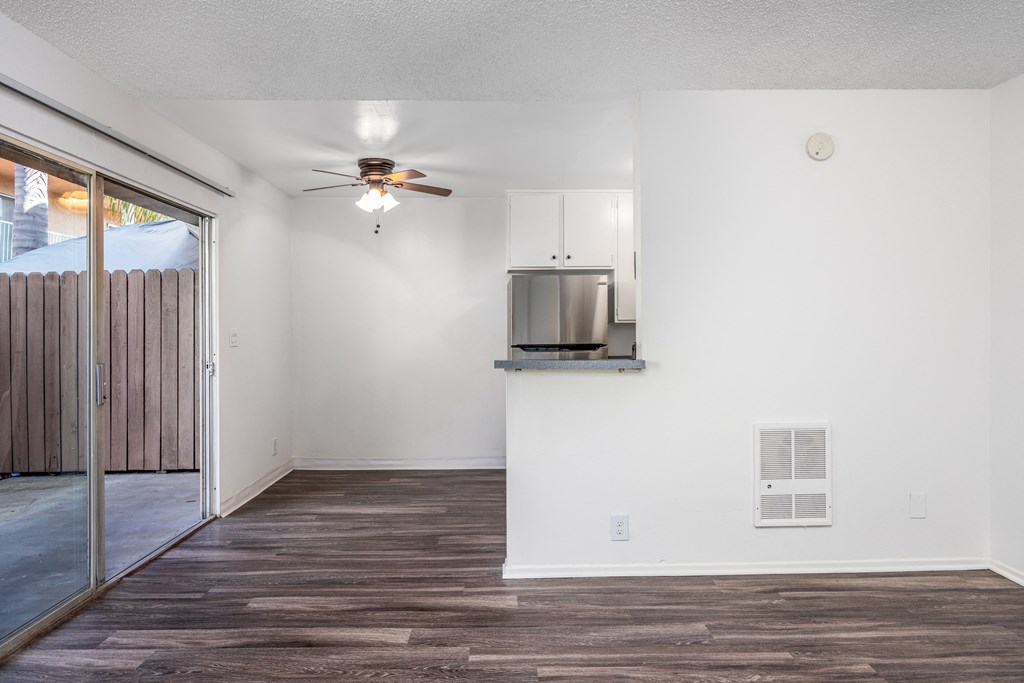 an empty living room with a ceiling fan and a sliding glass door