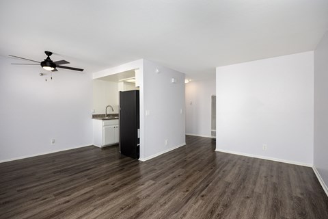 an empty living room with white walls and a ceiling fan
