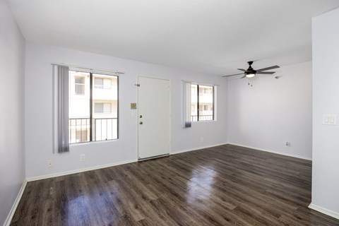 an empty living room with white walls and a ceiling fan