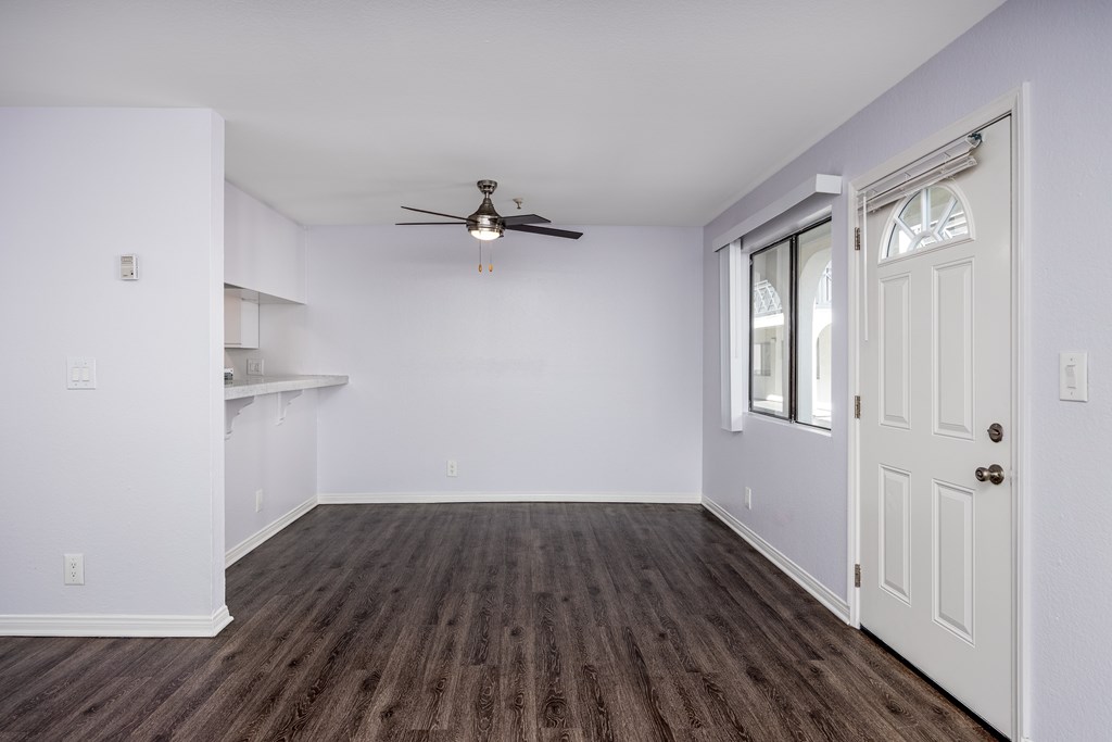 A room with a ceiling fan and wooden flooring.