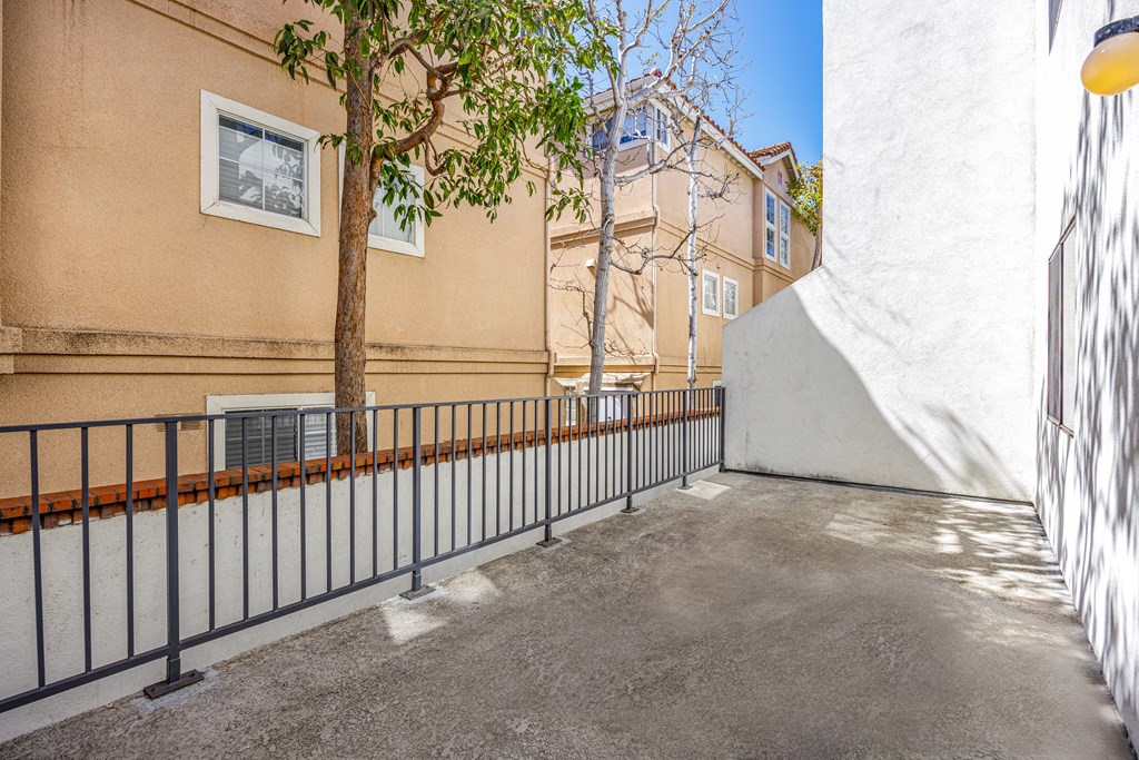 A tree is in front of a building with a white wall and a black fence.