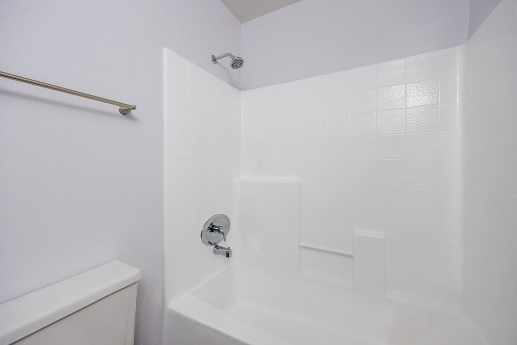 A white bathroom with a tub and toilet.